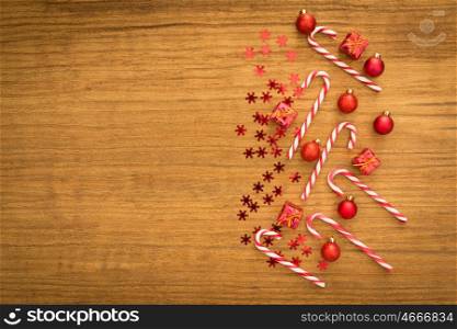 Candy canes with Christmas balls on a wooden background. Xmas decoration