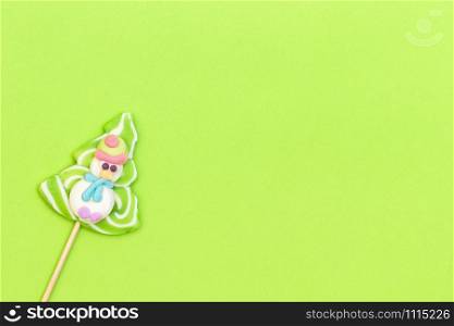 Candy lollipop of funny snowman and Christmas tree on green background. Bright creative layout for Christmas, New Year or winter holidays. Flat lay, Cope space, Top view, Greeting card. Candy lollipop of funny snowman and Christmas tree on green background.