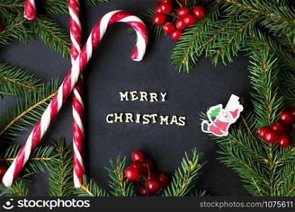 Candy on black background with branches of trees. The inscription Merry Christmas.. Candy on black background with branches of trees. The inscription Merry Christmas