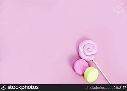 Candy sweets concept. Pink lollypop and donuts, macarons on pink background, copy space top view space for text. Candy sweets concept. Pink lollypop and donuts, macarons on pink background, copy space top view