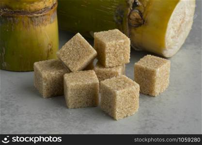Cane sugar cubes and fresh sugar cane in the background