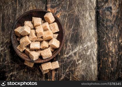 Cane sugar in a bowl. On a wooden background.. Cane sugar in a bowl.