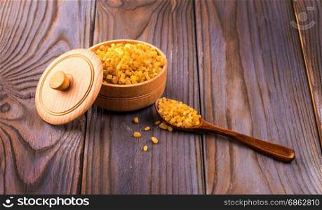 Cane sugar in a wooden cup with spoon on a wooden table