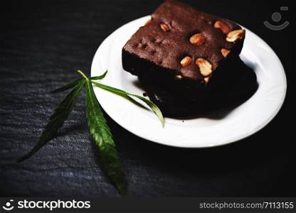 cannabis food snack for health / brownies with marijuana leaf herb on white plate dark background