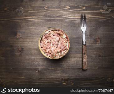 Canned beef with vintage fork on wooden rustic background top view close up