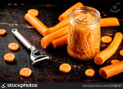 Canned carrots in a glass jar on the table. Against a dark background. High quality photo. Canned carrots in a glass jar on the table.