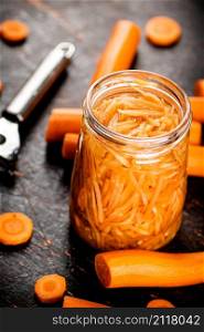 Canned carrots in a glass jar on the table. Against a dark background. High quality photo. Canned carrots in a glass jar on the table.