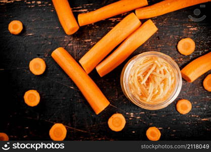 Canned carrots in a glass jar on the table. Against a dark background. High quality photo. Canned carrots in a glass jar on the table.