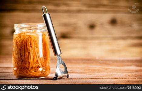 Canned carrots in a glass jar on the table. On a wooden background. High quality photo. Canned carrots in a glass jar on the table.