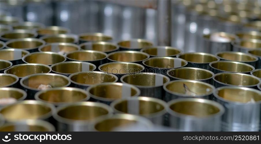 Canned fish factory. Food industry. Many can of sardines on a conveyor belt. Sardines in red tomato sauce in tinned cans at food factory. Food processing production line. Food manufacturing industry.