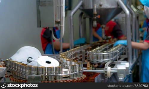 Canned fish factory. Food industry.  Sardines in red tomato sauce in tinned cans at food factory. Food processing production line. Food manufacturing industry. Many can of sardines on a conveyor belt.