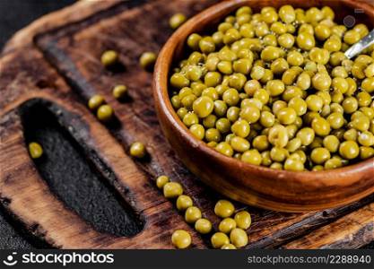 Canned green peas on a cutting board. On a black background. High quality photo. Canned green peas on a cutting board. 