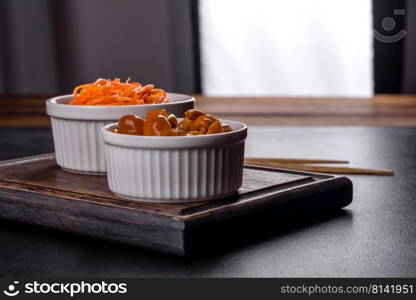 Canned mushrooms in a bowl on a dark background. Homemade pickled honey agarics mushrooms in a white bowl