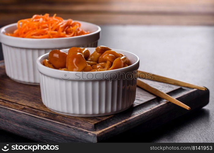 Canned mushrooms in a bowl on a dark background. Homemade pickled honey agarics mushrooms in a white bowl
