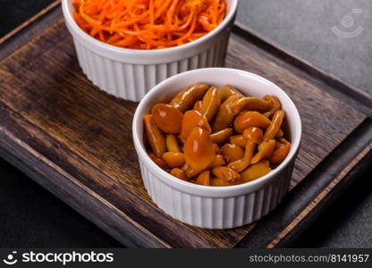 Canned mushrooms in a bowl on a dark background. Homemade pickled honey agarics mushrooms in a white bowl