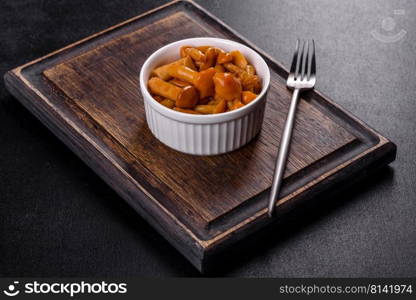 Canned mushrooms in a bowl on a dark background. Homemade pickled honey agarics mushrooms in a white bowl