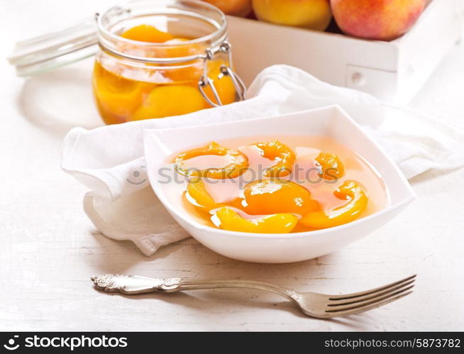 canned peaches in a bowl on wooden table