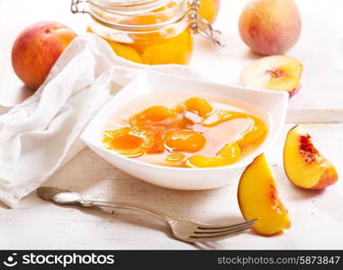 canned peaches in a bowl on wooden table