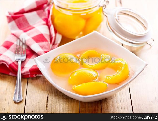 canned peaches in a bowl on wooden table
