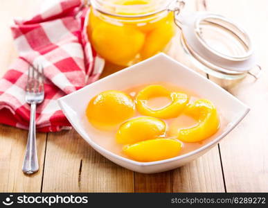 canned peaches in a bowl on wooden table