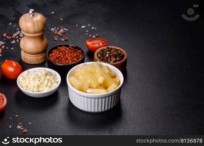Canned pineapple chunks. Pineapple pieces on dark background. Canned pineapple chunks in a white bowl on a dark concrete background