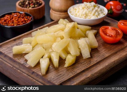 Canned pineapple chunks. Pineapple pieces on dark background. Canned pineapple chunks in a white bowl on a dark concrete background