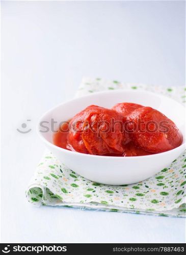 Canned tomatoes in bowl over red napkin, selective focus