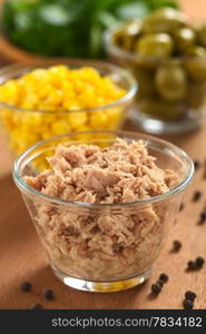 Canned tuna in glass bowl with fresh salad ingredients (sweet corn, green olives and watercress) in the back (Selective Focus, Focus one third into the tuna) . Tuna in Glass Bowl