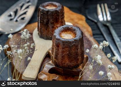 Canneles (Caneles) de Bordeaux Recipe is a small pastry with rum and vanilla on a wooden plate. Traditional French sweet dessert. tasty snacks. Oblique view from the top.