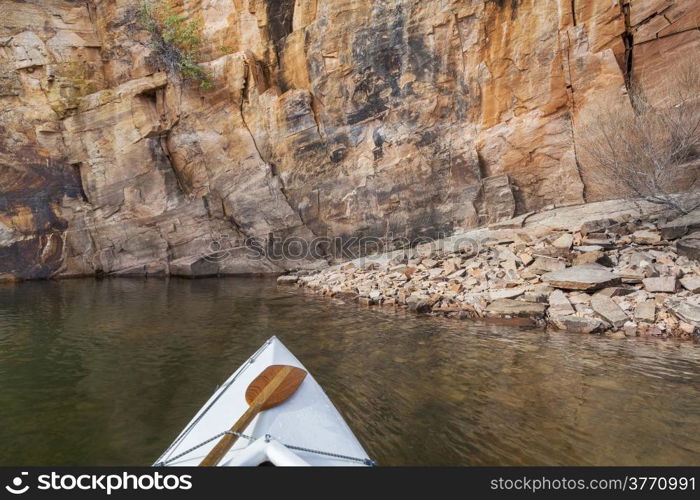 canoe bow with a paddle on Horsetooth Reservoir with a high sandstone cliff, Collins, Colorado