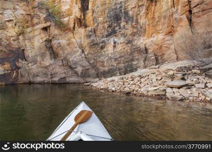 canoe bow with a paddle on Horsetooth Reservoir with a high sandstone cliff, Collins, Colorado
