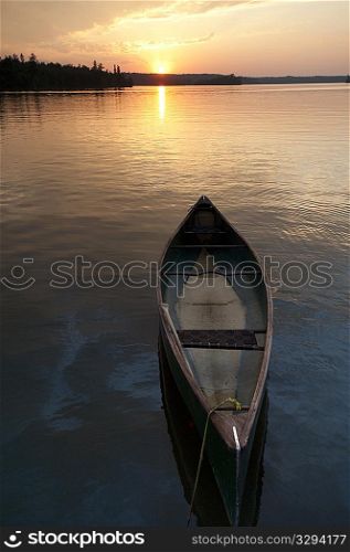 Canoe on the water with the sunset in horizon at Lake of the Woods, Ontario