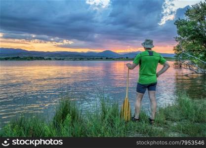 canoe paddler watching sunset over Rocky Mountains from a lake shore in Colorado near Loveland
