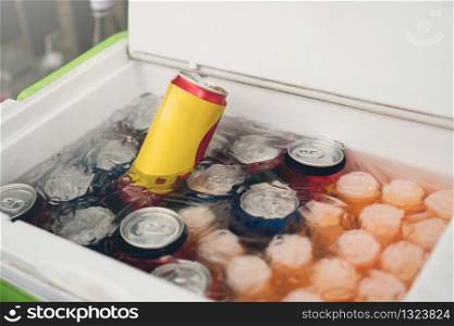 Cans of soft drinks in an ice box.