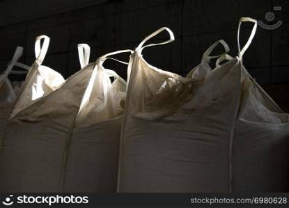 Canvas grenade bags with grain stored in a warehouse, with light rays and shadows