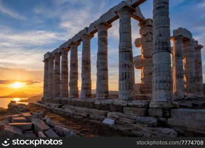 Cape Sounio sunset at Sounion with ruins of the iconic Poseidon temple. One of the Twelve Olympian Gods of ancient Greek religion and mythology. God of the sea, earthquakes. Aegean coast, Greece.. Poseidon temple ruins on Cape Sounio on sunset, Greece