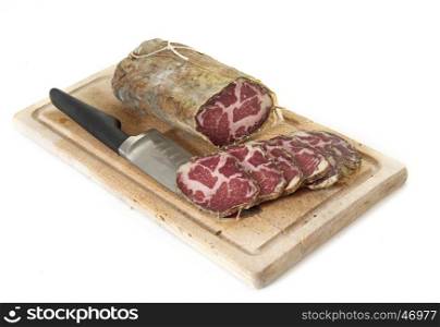 Capocollo and slice in front of white background