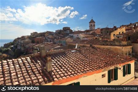 Capoliveri village against the sun, with the characteristic roofs, Elba Island, Italy