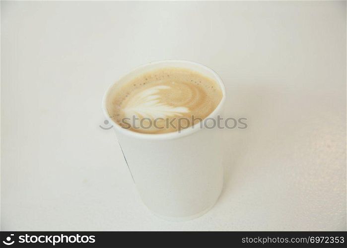 Cappuccino coffee in coffee paper cup in white tone coffeeshop