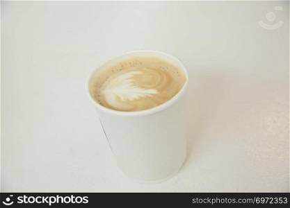 Cappuccino coffee in coffee paper cup in white tone coffeeshop