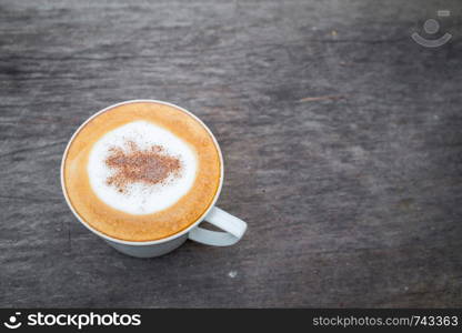 Cappuccino coffee in white cup on wooden table