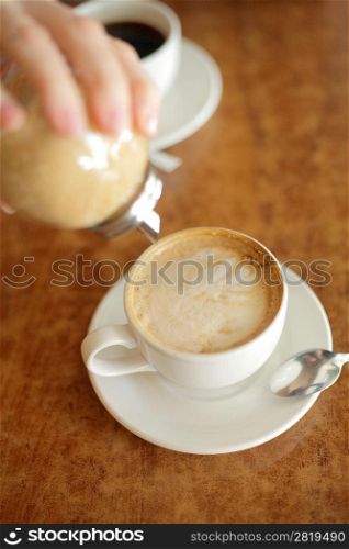 cappuccino cup on the brown wooden table with sugar