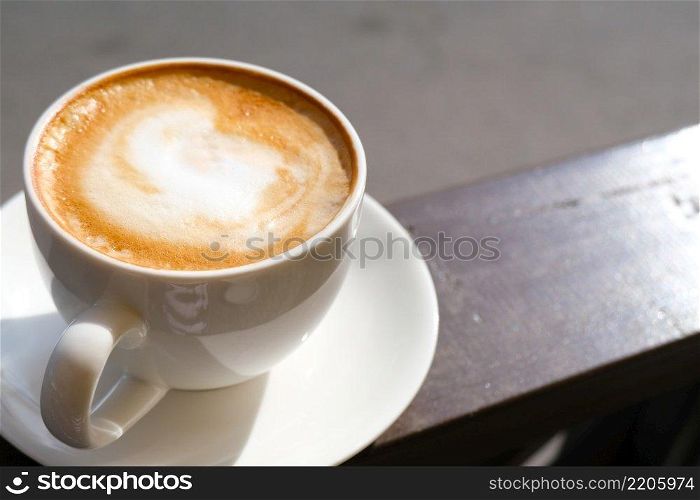 Cappuccino in white cup on sunlight at cafe. Copyspace. Bewerages, coffee lovers and morning menu concept. Nature background.. Cappuccino in white cup on sunlight at cafe. Copyspace. Bewerages, coffee lovers and morning menu concept. Brown background