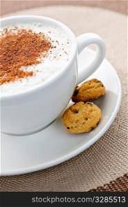 Cappuccino or latte coffee in cup with frothed milk and cookies