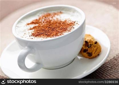 Cappuccino or latte coffee in cup with frothed milk and cookies