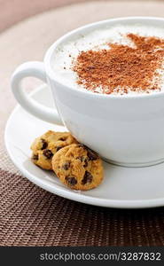 Cappuccino or latte coffee in cup with frothed milk and cookies