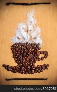 Cappuccino time. Roasted coffee beans placed in shape of cup with white froth vanilla pods on wooden surface background