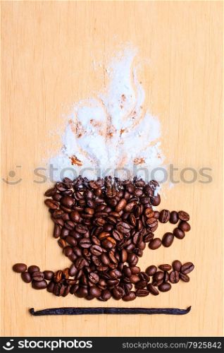 Cappuccino time. Roasted coffee beans placed in shape of cup with white froth vanilla pod on wooden surface background