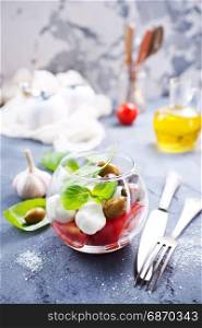 caprese salad in glass bowl and on a table