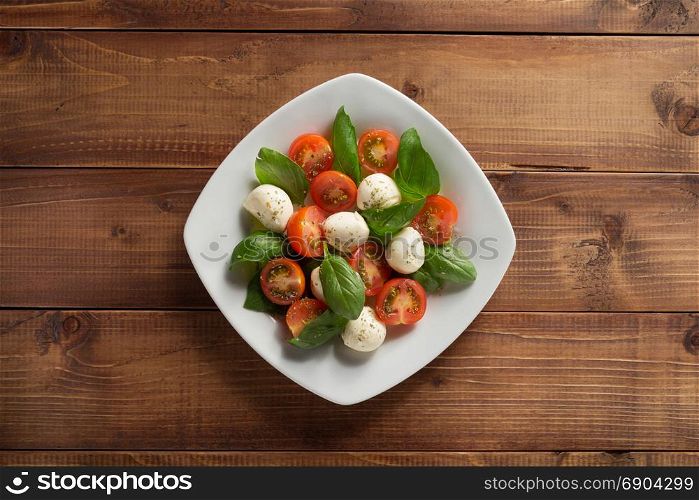 caprese salad in plate at wooden background